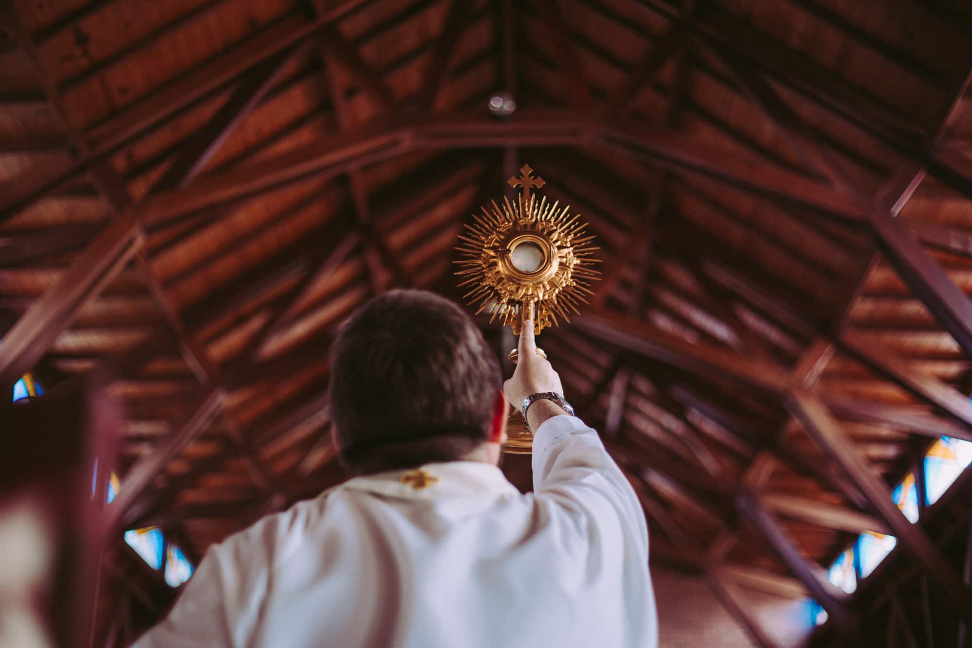 Imagen del Santisimo Sacramento sostenido por un sacerdote. Descubre el significado de la Eucaristía, Misa, y nuestra participación en ella en nuestro artículo de las 100 frases de santos sobre la Misa. Encuentra horarios de misa, adoración, y confesión cerca tuyo en la aplicación de Horarios de Misa en tu celular.